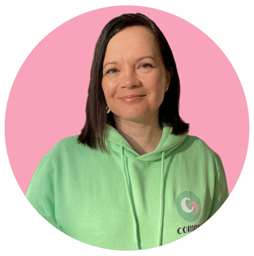 Smiling person in a light green hoodie against a pink circular background.